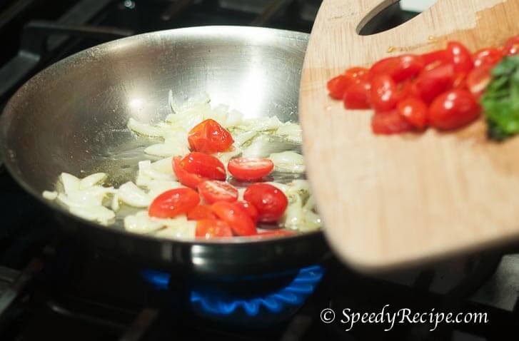 onion, grape tomato, and basil cooking in pan